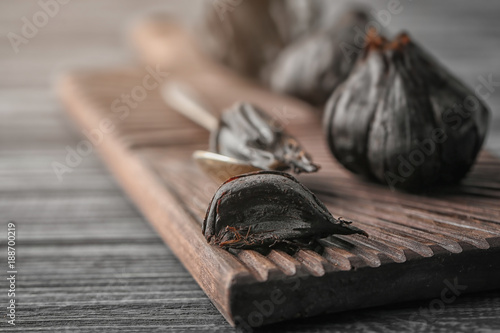 Black garlic (Allium sativum) on wooden board