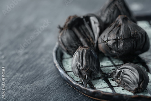 Plate with black garlic (Allium sativum) on table