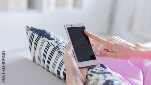 Woman at home relaxing reading on the smartphone 
