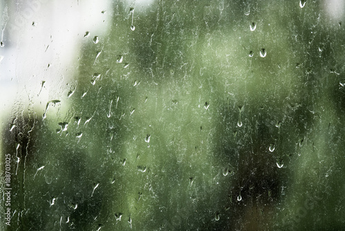Raindrops on a dirty window pane with out-of-focus background