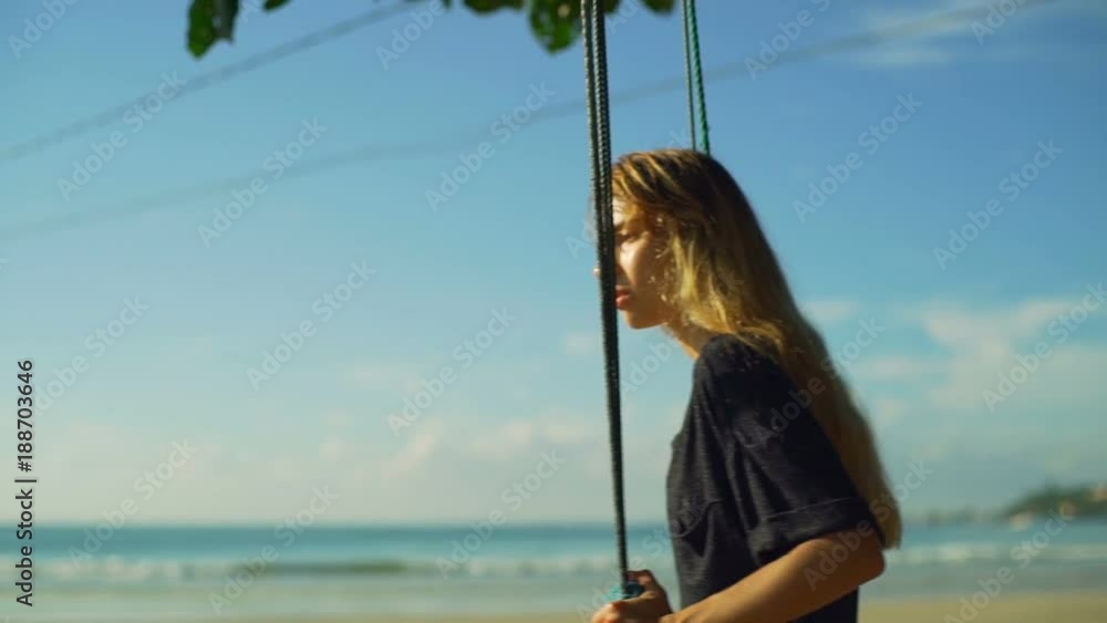Young blonde girl sit and teeter on swing on the beach sunrise rapid slow motion Young blonde girl sit and teeter on swing on the beach sunrise rapid slow motion