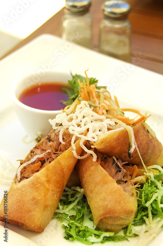 A spring roll dish werved with chili sauce and vegetables