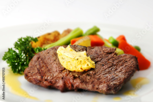 A fried tenderloin steak with butter and various vegetables
