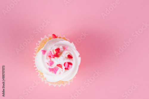 cupcake with heart confetti on a pink background for valentine's day