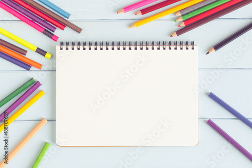 Blank notebook with colorful pencil on blue wooden table,top view