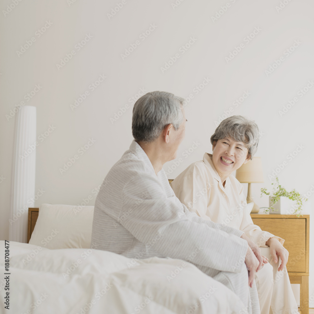 ベッドに座り談笑をするシニア夫婦 ベッドに座り談笑をするシニア夫婦