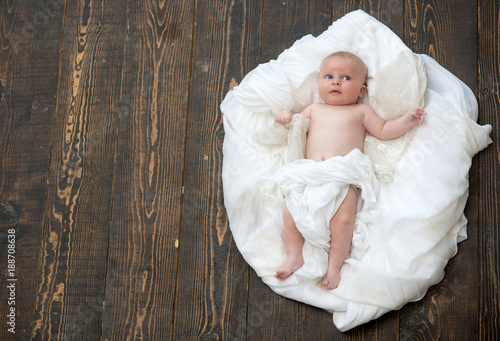 Infant covered with white blanket. Baby lying on soft duvet photo