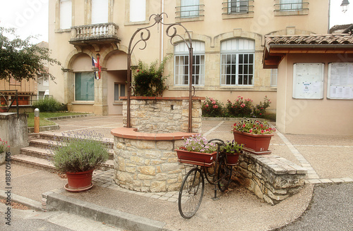 Picturesque village square, featuring a well, old bicycle and flower pots, village in the South of France