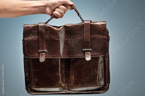 A man holding a brown leather travel bag photo