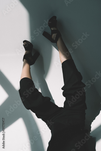 cropped image of fashionable girl lying in black clothes on white