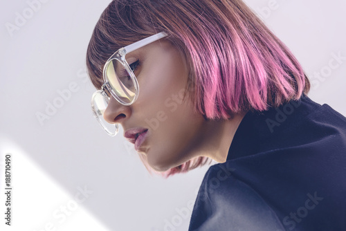 portrait of stylish girl with pink hair and glasses on white