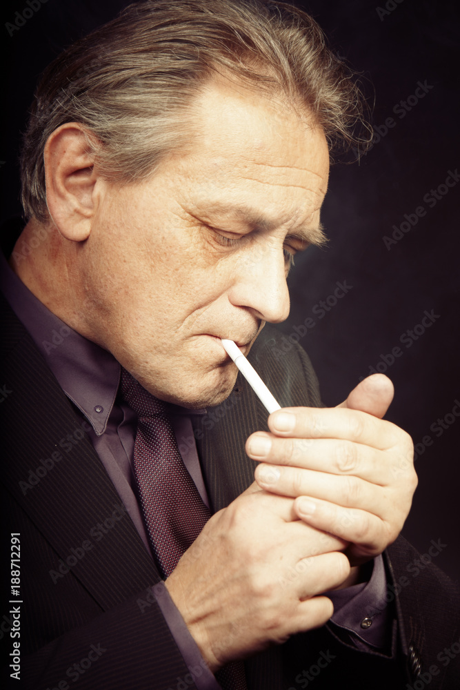 Fototapeta premium Older caucasian man trying electronic cigarette on black background