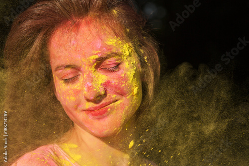 Closeup portrait of wonderful brunette girl with Holi paint blowing into her face