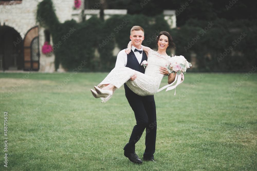 Fototapeta premium Lovely happy wedding couple, bride with long white dress posing in beautiful city