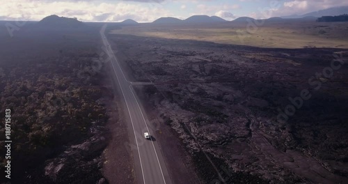 Hawaii Mauna Kea drive drone aerial moving backwards over highway with lava fields and mountains