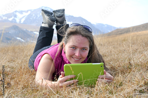 Girl with tablet PC is in a mountainous area photo