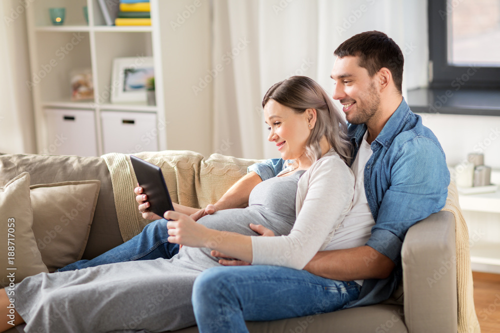 man and pregnant woman with tablet pc at home