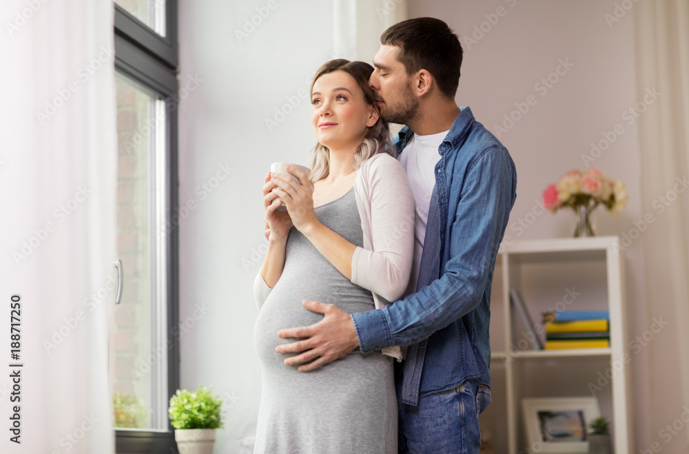 man hugging pregnant woman at window at home man hugging pregnant woman at window at home