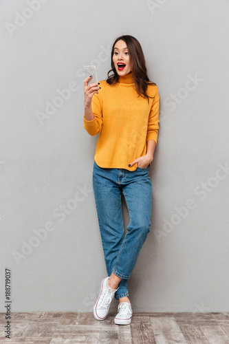 Full length image of Surprised happy brunette woman in sweater