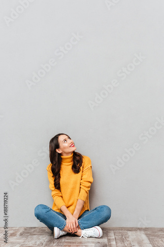 Vertical image of Smiling brunette woman sitting on the floor