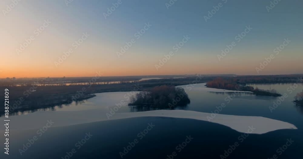 Aerial.Winter sunset over a country road outside the city. Reflections of trees on water and ice.Red trees in the sunset sun. Aerial.Winter sunset over a country road outside the city. Reflections of trees on water and ice.Red trees in the sunset sun.