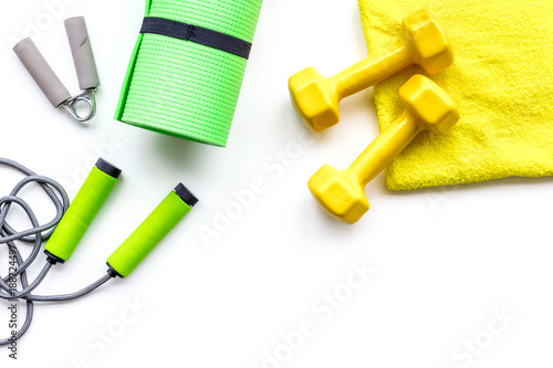 Do fintess in gym. Jump rope, expander, dumbbells and mat on white background top view copy space