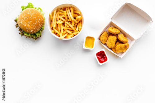 Fast food. Chiken nuggets, burgers and french fries on white background top view space for text