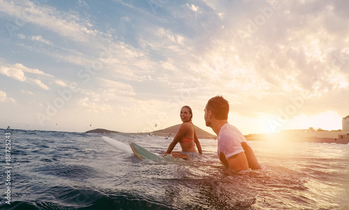 Canvas Print Fit couple surfing at sunset