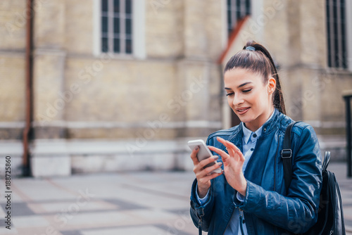 Beautiful brunette girl using smartphone outdoor.