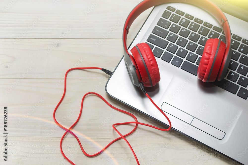 Obraz premium the laptop and red wooden headphones on a light background.