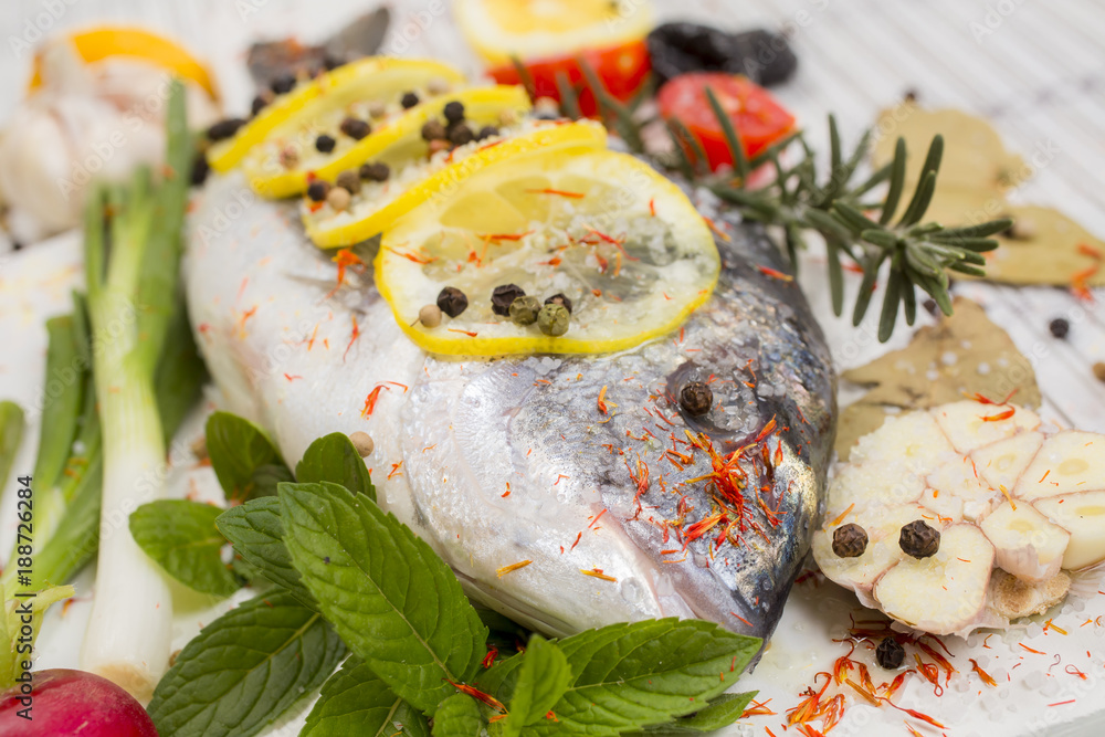 sea bass with vegetables and spices on white wooden background sea bass with vegetables and spices on white wooden background
