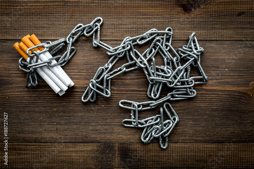 Quit smoking. Cigarettes in chains on dark wooden background top view