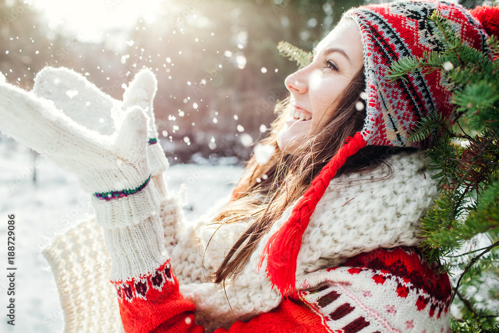 Young woman in red sweater throws snow. Winter activities.