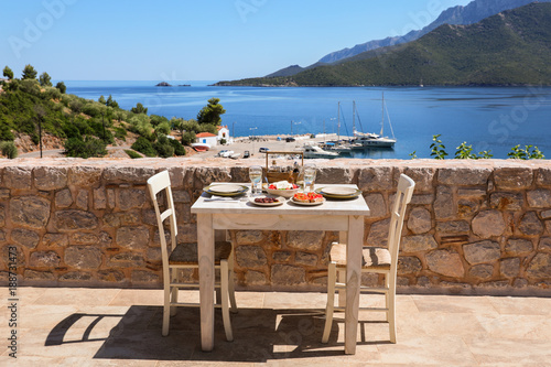 A table served for two with snacks and drinks on the summer terrace of the hotel room by the seascape.