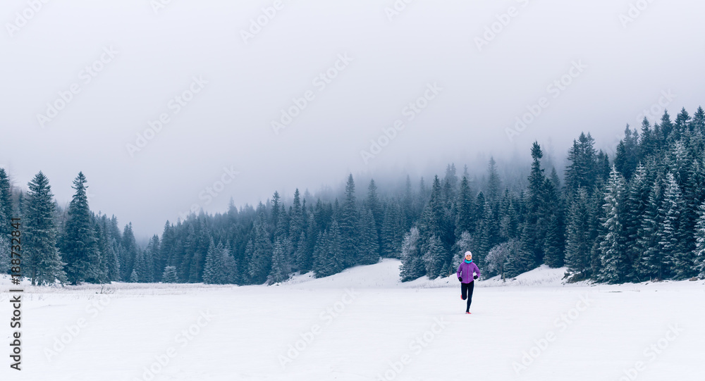 Woman running on winter trail in forest, fitness inspiration