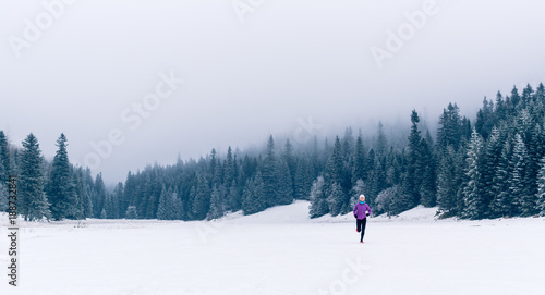 Woman running on winter trail in forest, fitness inspiration