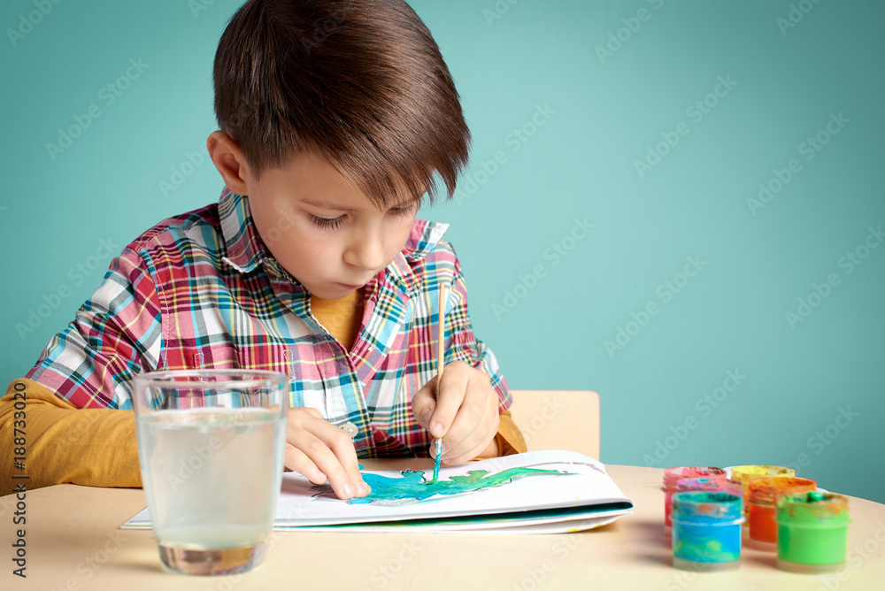 Caucasian boy is carefully painting with watercolors. Caucasian boy is carefully painting with watercolors.