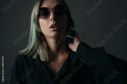 Young woman in sunglasses on a black background. Studio portrait