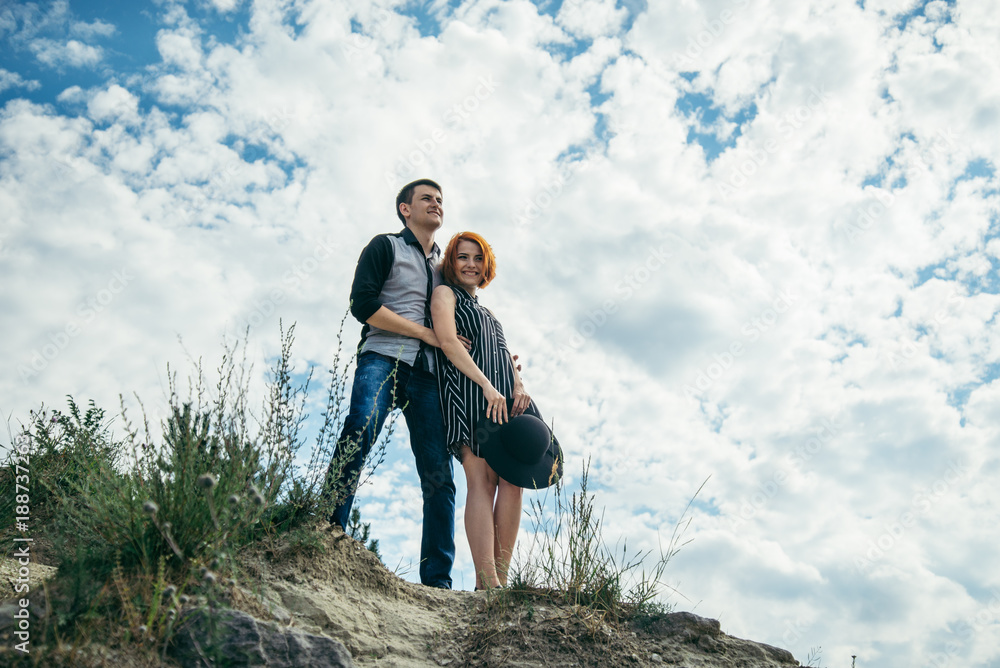 young man with woman stands on the hill and looks straight ahead