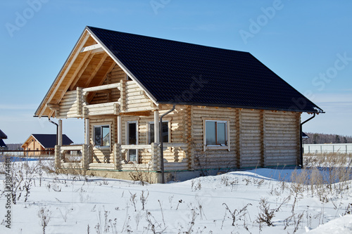 Wooden house at winter, unfinished construction, sunny day