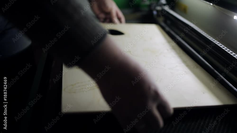 The man opens the lid of the laser systems for cutting plywood with a laser The man opens the lid of the laser systems for cutting plywood with a laser