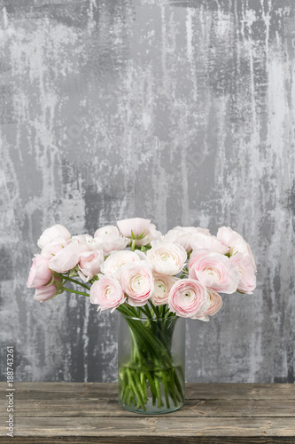 Vase with beautiful bouquet of ranunculus flowers on wooden table. rustic background with copy space. Close up Persian buttercup flower.