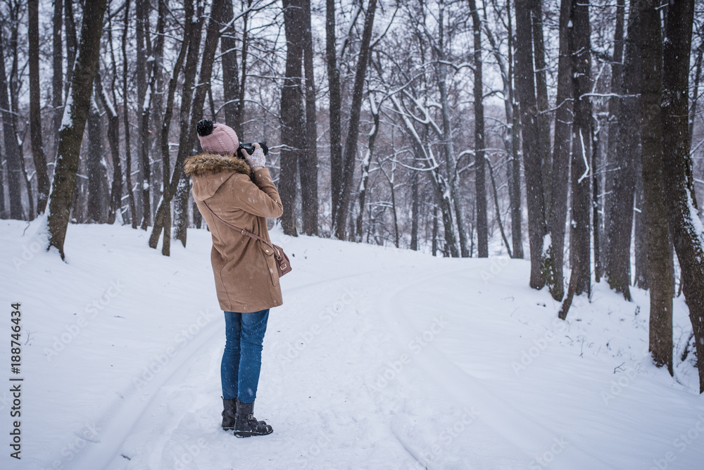 Young woman tourist takes photos of nature in winter