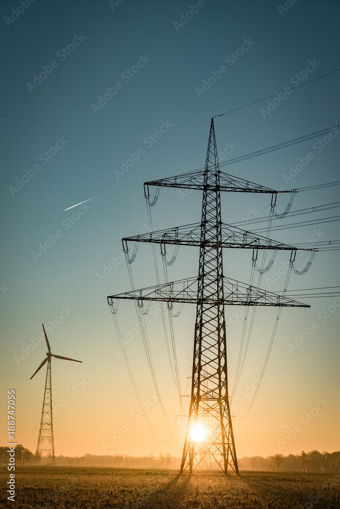 Netzausbau, Strommast mit Stromleitungen und Windrad im Hintergrund, Hochformat