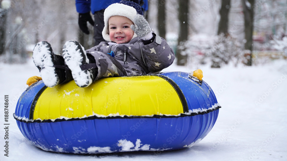 boy of two years rolling on tubing in the park in winter. boy of two years rolling on tubing in the park in winter.