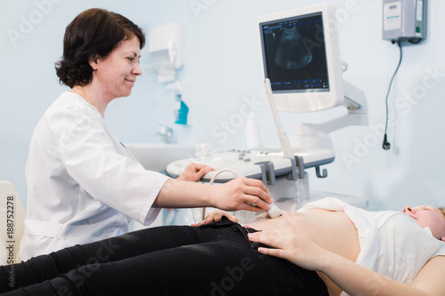 pregnant woman and doctor hands with ultrasound equipment
