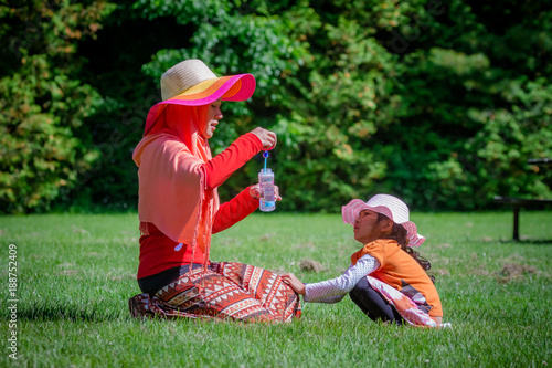 Mother and child from Asia play bubble on a park in Canada