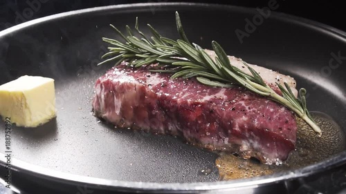 Slices of butter falls on a frying pan to the steak