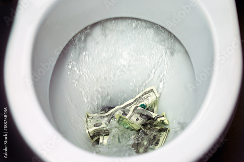 Flush money down the toilet, throws dollar bills in the toilet, loss concept, close up, selective focus