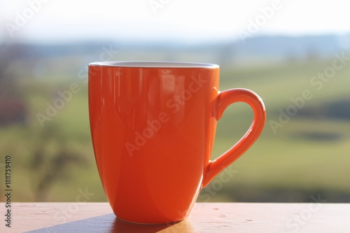 Kaffeetasse, orange, auf dem Balkon, Landschaft im Hintergrund